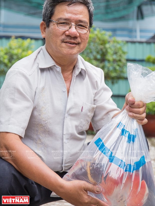 Ông Võ Tuấn Kiệt và con cá dĩa thương phẩm. Ảnh: Báo ảnh Việt Nam Làm giàu từ Nông nghiệp