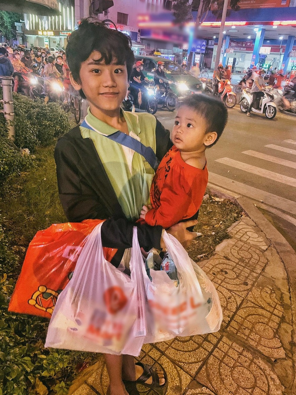 Cậu bé bế em ăn xin trên phố Sài Gòn
