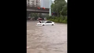 Clip: Cô gái trèo lên nắp capo ung dung lướt điện thoại giữa biển nước