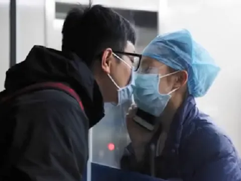 Nụ hôn qua cửa kính cách ly của nữ y tá hoãn kết hôn để vào 'vùng dịch'